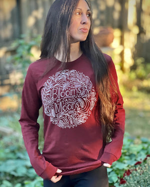 Long sleeve maroon t-shirt with graphic of Blooms and Moons handlettering and designs with leaves