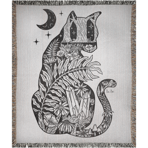 Woven blanket with cat silhouette and night scene of moon, plants leaves, blooms, mushrooms, and a crystal cluster.